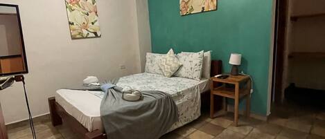 A bedroom with a bed, a nightstand, a ceiling fan, and two wall-mounted paintings.