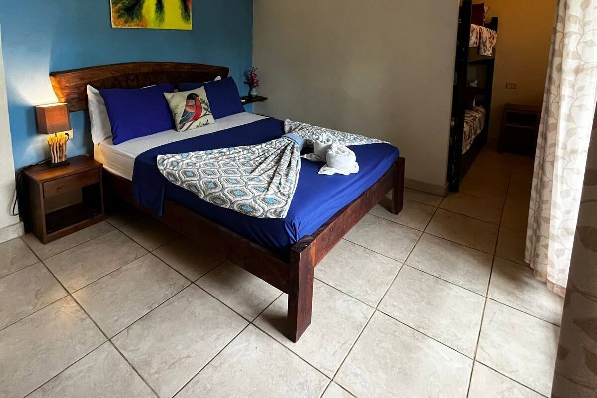 A bedroom with a bed, a nightstand, a wall-mounted air conditioner, and a painting.
