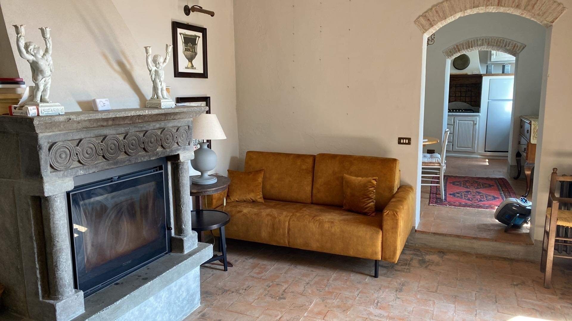 A living room with a fireplace, a sofa, and a dining area visible through an archway.
