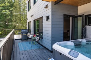 A deck with a hot tub, outdoor grill, and seating area.