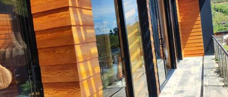 A modern building with large glass doors, wooden paneling, and a covered outdoor area with a view of the landscape.