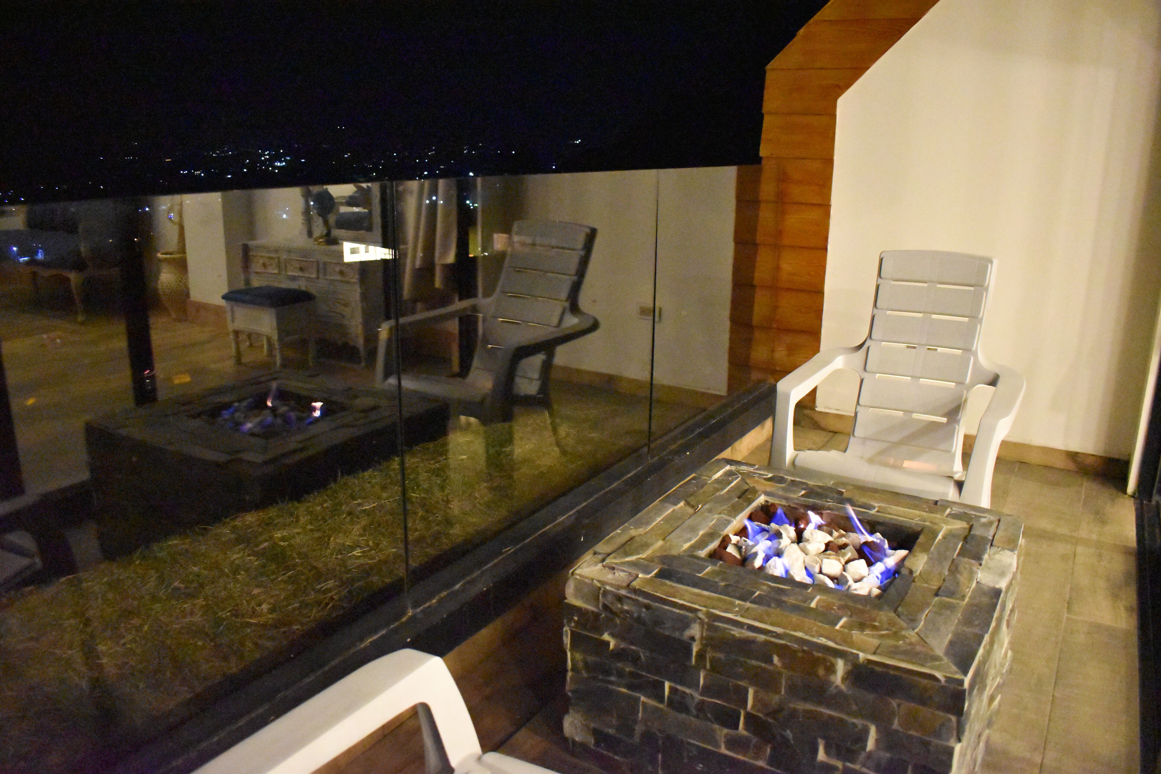 An outdoor seating area with a stone fire pit and two chairs.