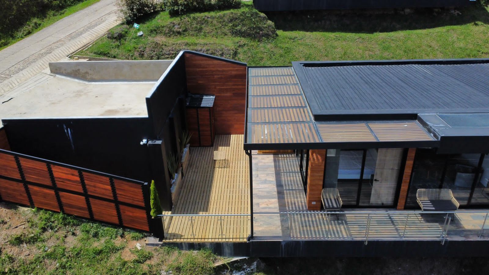 A modern house with a large deck, a covered outdoor area, and a glass-enclosed room.