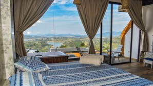 A bedroom with a large bed, a view of a lake, and a dining area with a table and chairs. - MONTECIELO HOSTING GUATAPE (El Peñol)