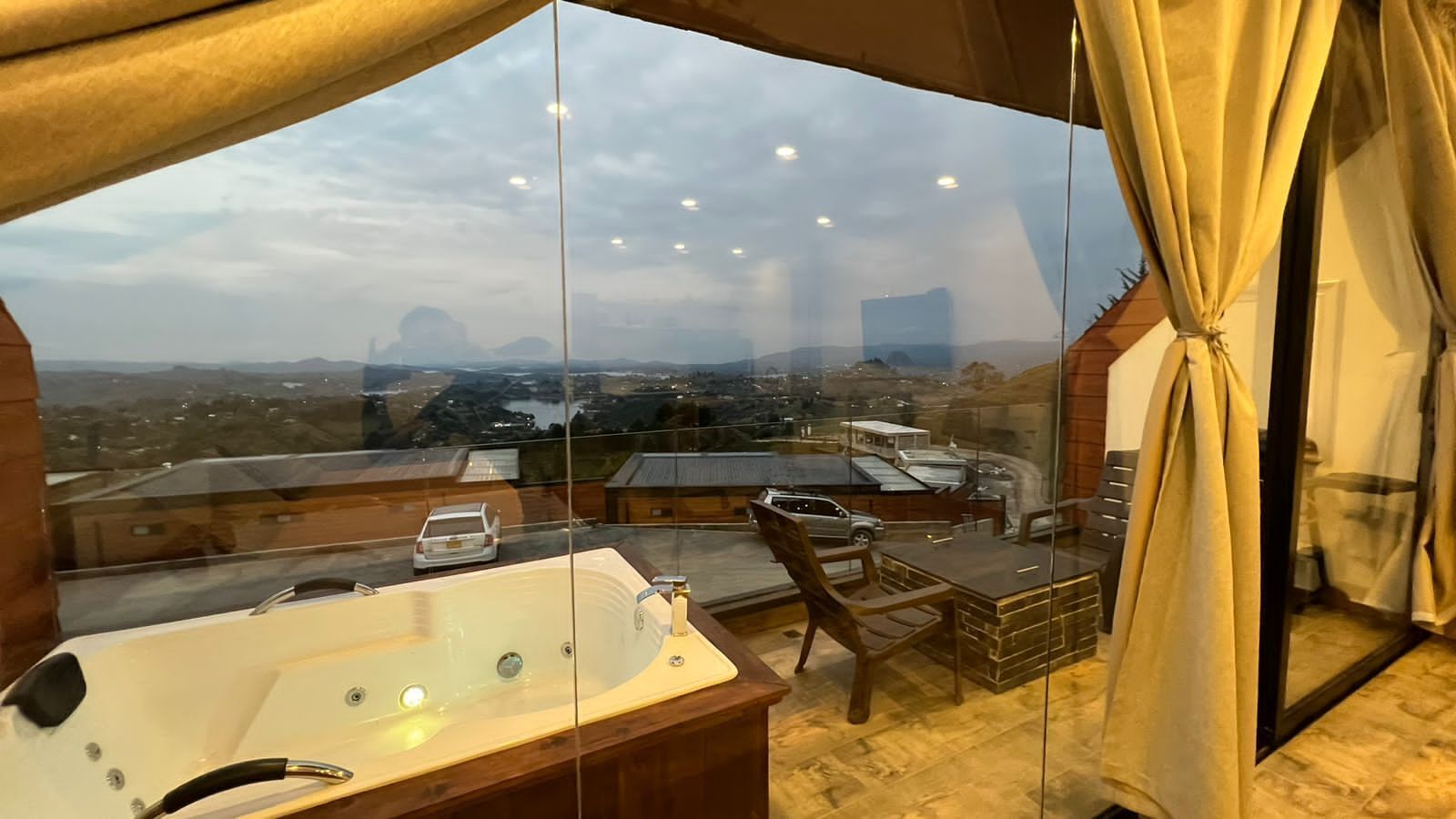 A balcony with a hot tub, a wooden chair, and a table.