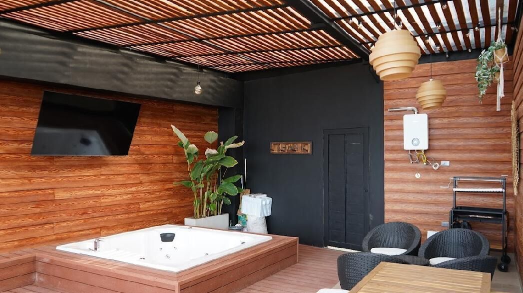 A spa area with a hot tub, wooden walls, and wicker furniture.