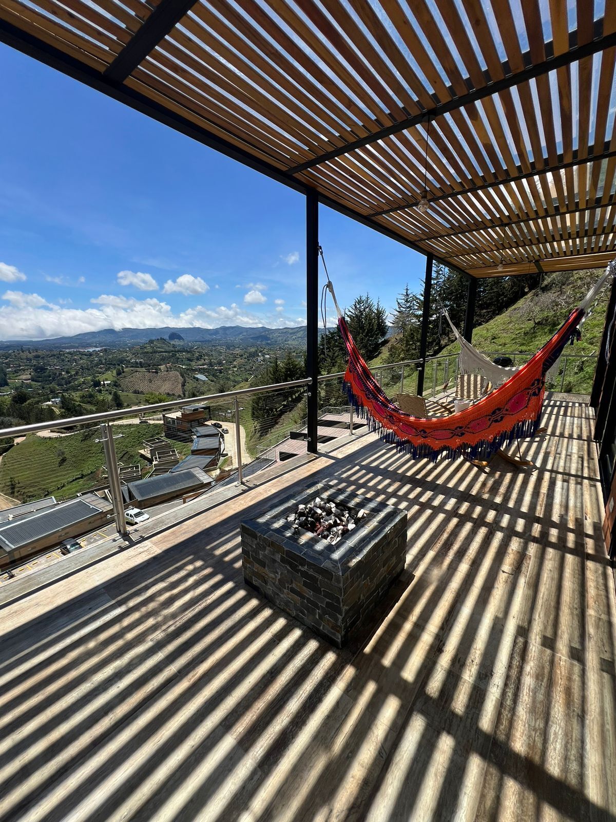 A rooftop terrace with a hammock, a fire pit, and a view of the landscape.
