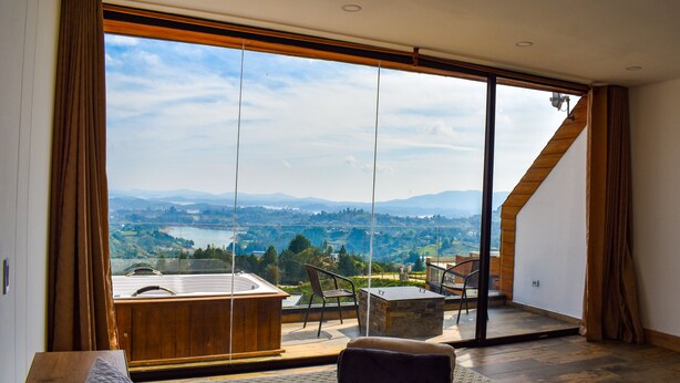 A bedroom with a large sliding glass door leading to a balcony with a view of a lake and mountains. - MONTECIELO HOSTING GUATAPE (El Peñol)