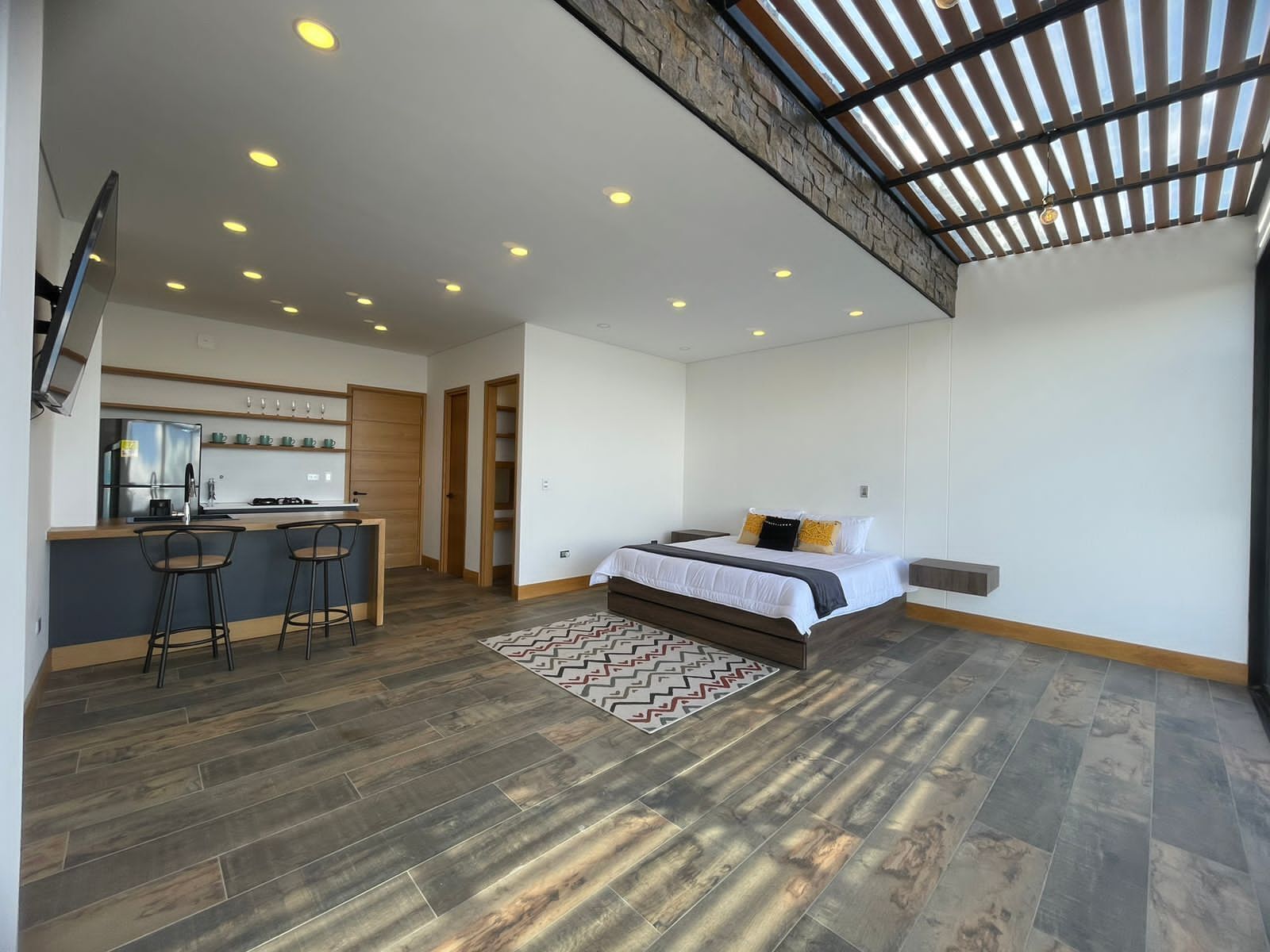 A modern, open-plan living space with a kitchen, dining area, and a large bed.