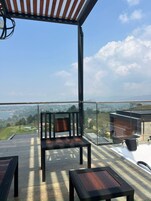 A balcony with a view of a landscape, a glass railing, and a white bathtub.