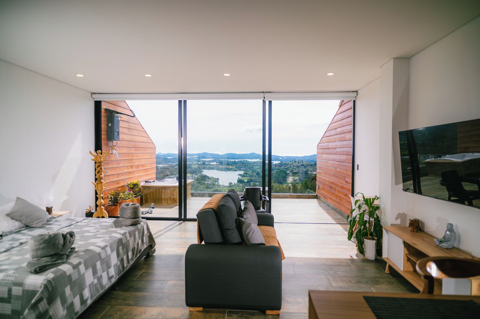 A modern living room with a large window, a sofa, a bed, and a TV.