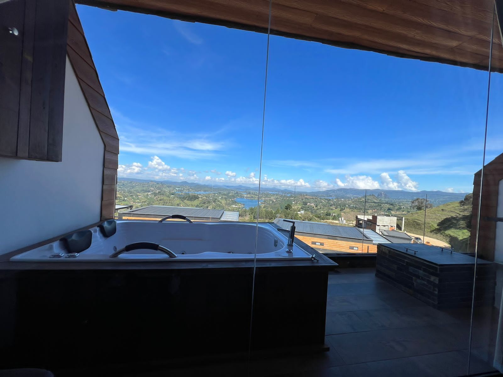 Ein moderner Außenbereich mit Whirlpool und freiem Blick auf die umliegende Landschaft und ferne Berge.