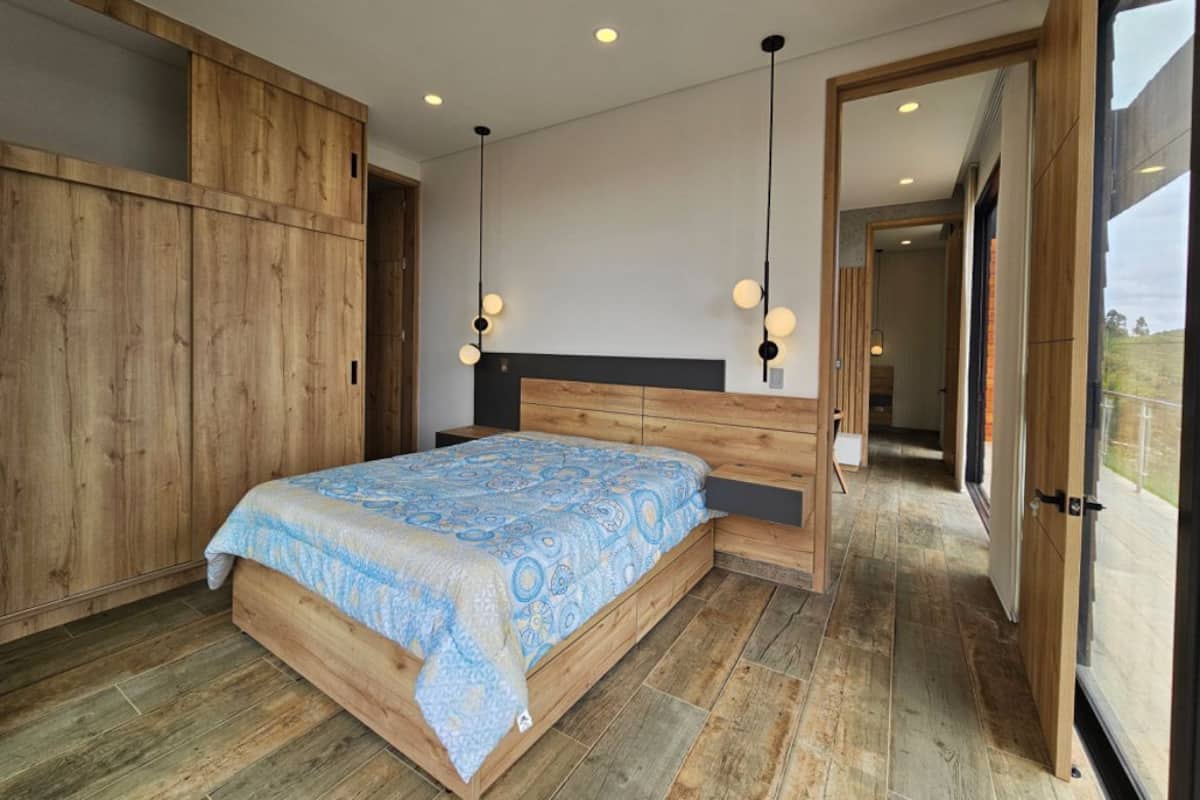 Une chambre à coucher avec un cadre de lit en bois, une couvre-lit à motifs et une tête de lit moderne.