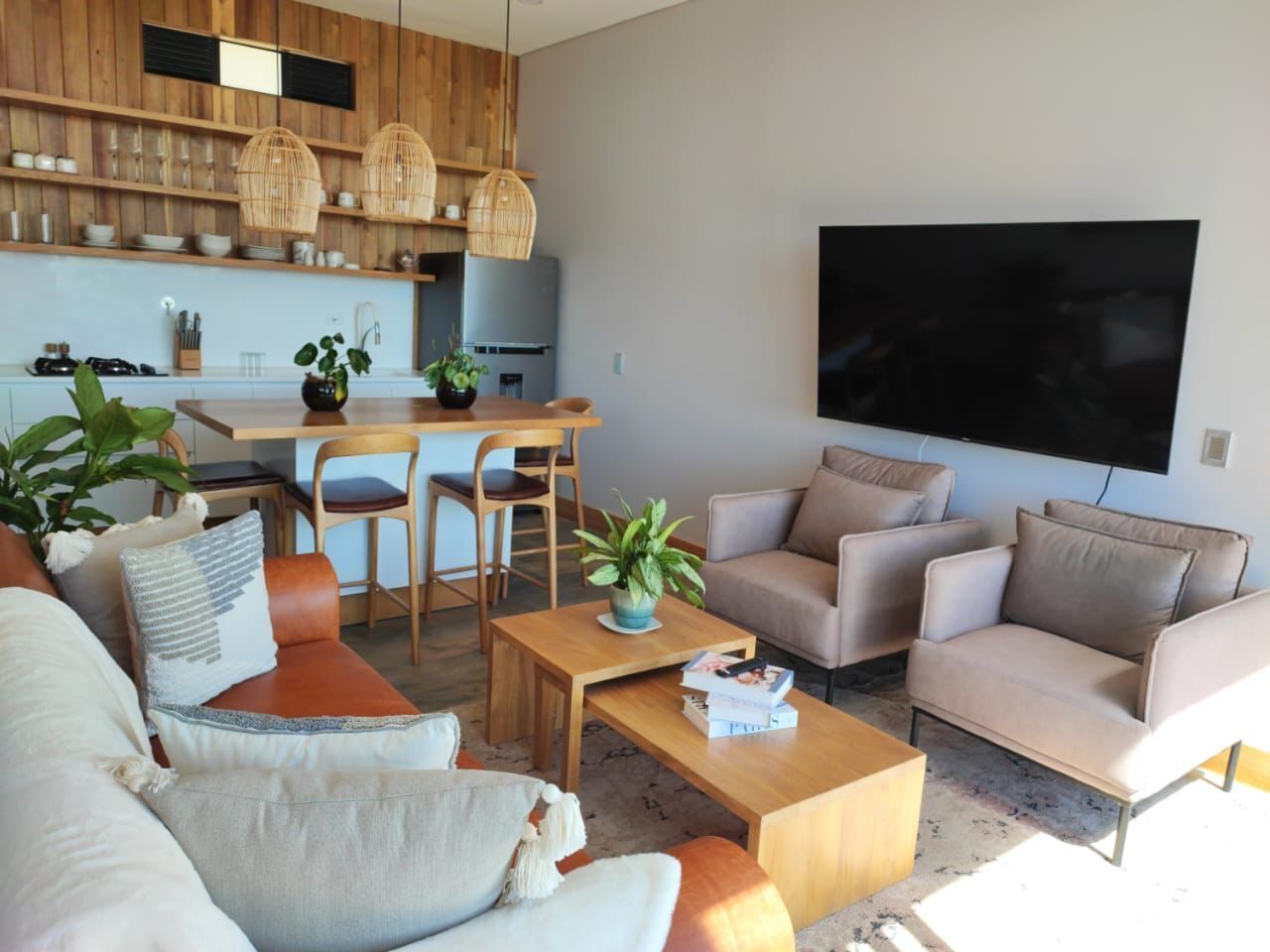 A modern living room with a sofa, armchairs, a coffee table, and a dining area with chairs and a table.