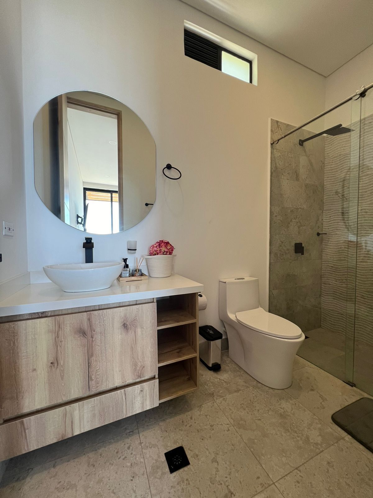 A modern bathroom with a large mirror, a sink, a toilet, and a shower area.