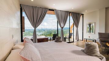 Un dormitorio con una cama grande, vistas al exterior, un área de descanso y un baño.