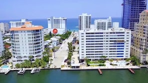 A coastal cityscape with high-rise buildings, a marina, and a clear view of the ocean.