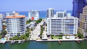 A coastal cityscape with high-rise buildings, a marina, and a clear view of the ocean.