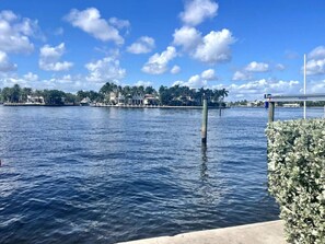 A waterfront view with a dock, calm water, and buildings in the background.
