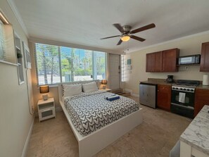A bedroom with a bed, bedside tables, a ceiling fan, and a window with blinds.