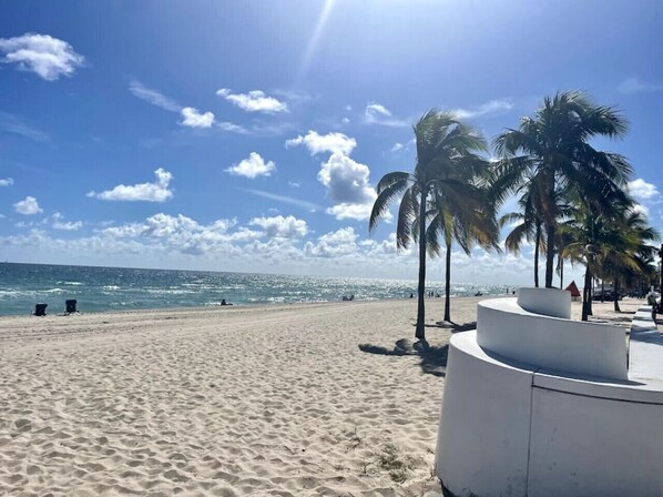 A beach with sand, palm trees, and a clear sky.