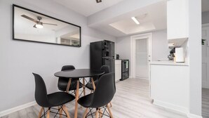 A modern kitchen with a refrigerator, a dining area with a table and chairs, and a ceiling fan. - Short Walk to Wilton Drive! Apt2 (Wilton Manors)