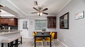 A kitchen with a dining table, yellow chairs, wooden cabinets, a ceiling fan, and a window with blinds. - Short Walk to Wilton Drive! Apt4 (Wilton Manors)