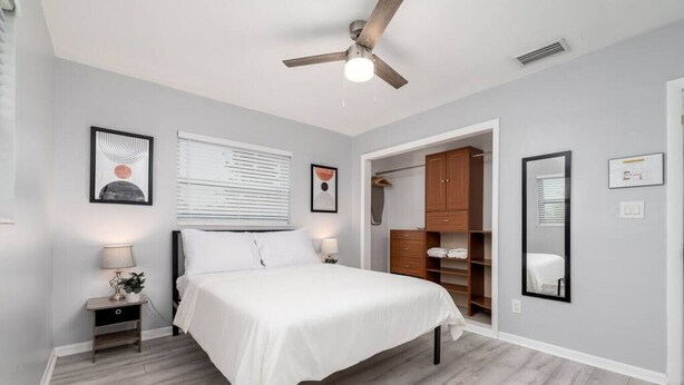 A bedroom with a bed, bedside tables, a ceiling fan, a wardrobe, and a mirror. - Short Walk to Wilton Drive! Apt4 (Wilton Manors)