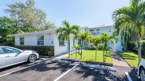 A building with a parking lot, palm trees, and a white car. - Short Walk to Wilton Drive! Apt5 (Wilton Manors)