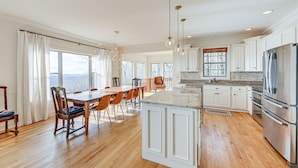 A spacious kitchen with wooden flooring, white cabinetry, and stainless steel appliances.