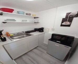 A compact kitchen with a sink, a coffee maker, and a microwave.