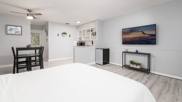 A modern bedroom with a large bed, a dining area with chairs, a kitchenette, and a TV mounted on the wall. - Just Off Wilton Drive! Apt 4 (Wilton Manors)