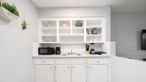 A modern kitchen with white cabinetry, a microwave, coffee maker, and a blender on the countertop. - Just Off Wilton Drive! Apt 4 (Wilton Manors)