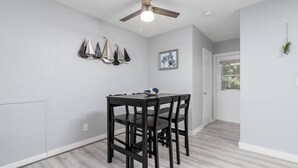A dining area with a table and chairs, a ceiling fan, and a door leading to another room. - Just Off Wilton Drive! Apt 4 (Wilton Manors)