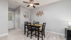 Un espace repas comprenant une table, des chaises, un ventilateur de plafond et un élément décoratif fixé au mur.