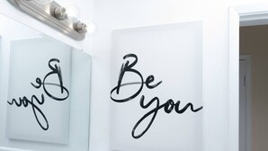 Une salle de bain avec un miroir et deux œuvres d’art murales inspirantes, l’une portant le mot « vous » et l’autre, la phrase « Soyez vous-même ».