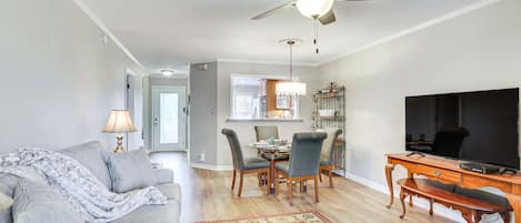 A living room with a sofa, a coffee table, a TV, and a dining area with chairs and a table.