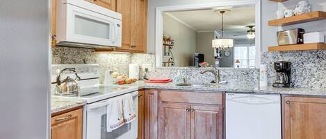 A kitchen with wooden cabinets, a white refrigerator, a microwave, a stove, and a dishwasher.