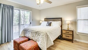 Un dormitorio con cama, mesita de noche, lámpara, ventilador de techo y ventana con persianas.