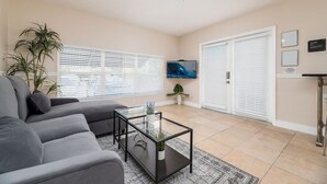 A living room with a sofa, a coffee table, a TV, and a ceiling fan.