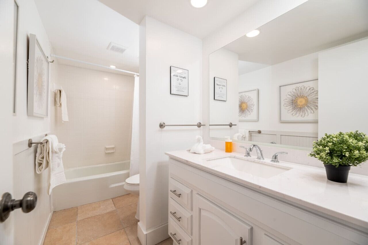 A modern bathroom with a bathtub, toilet, and vanity with a sink and mirror.