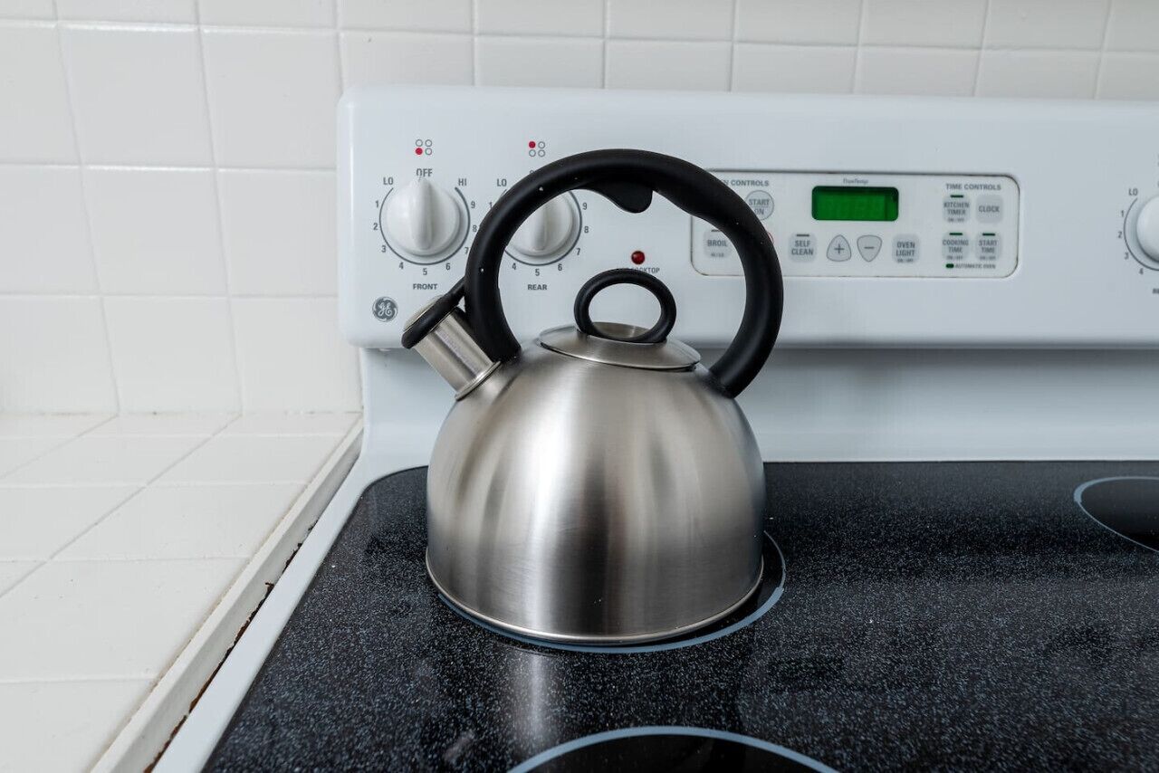 A kettle on a stove with a digital control panel.