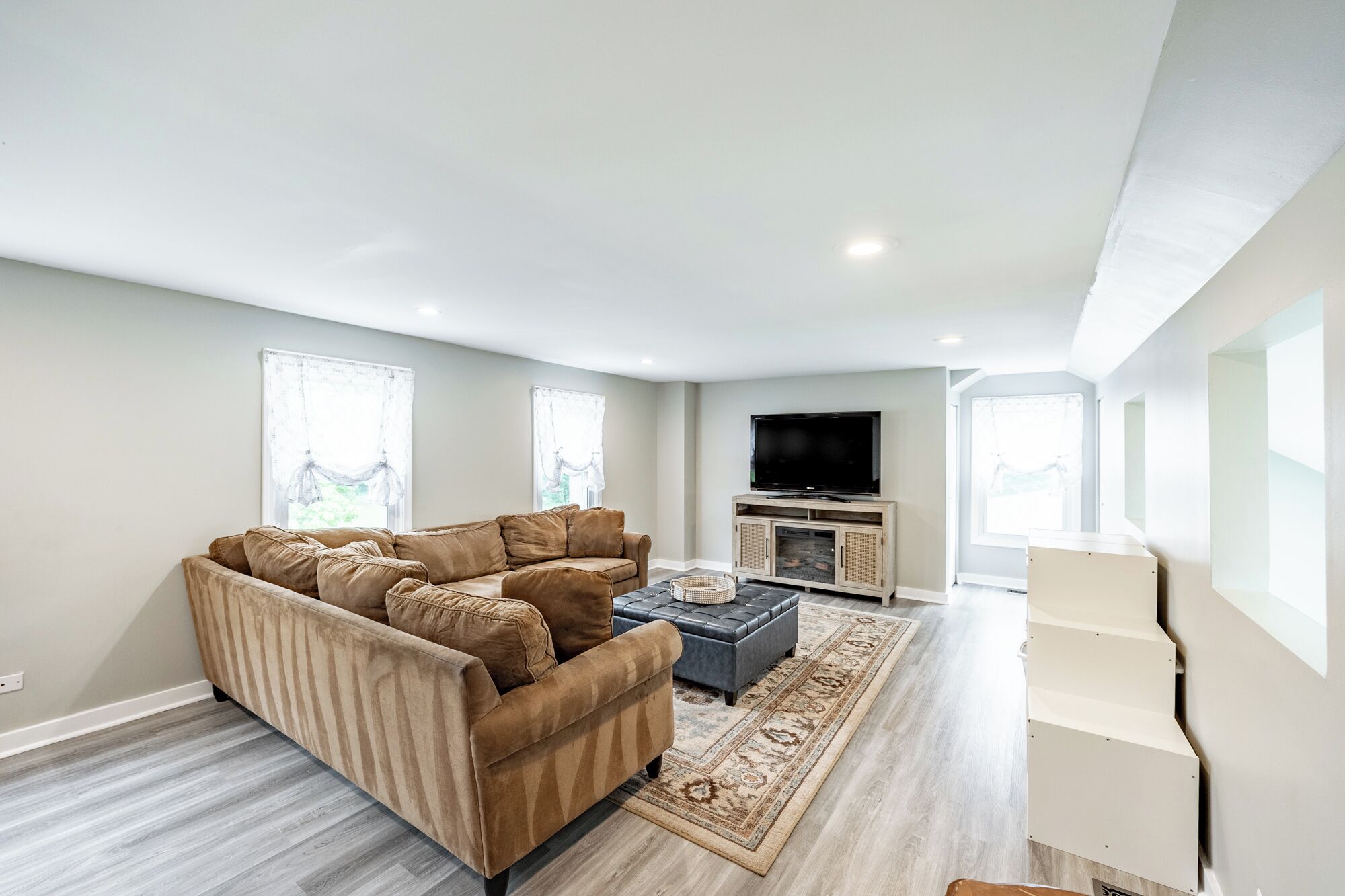 A modern living room with a sectional sofa, a flat-screen TV, and a fireplace.