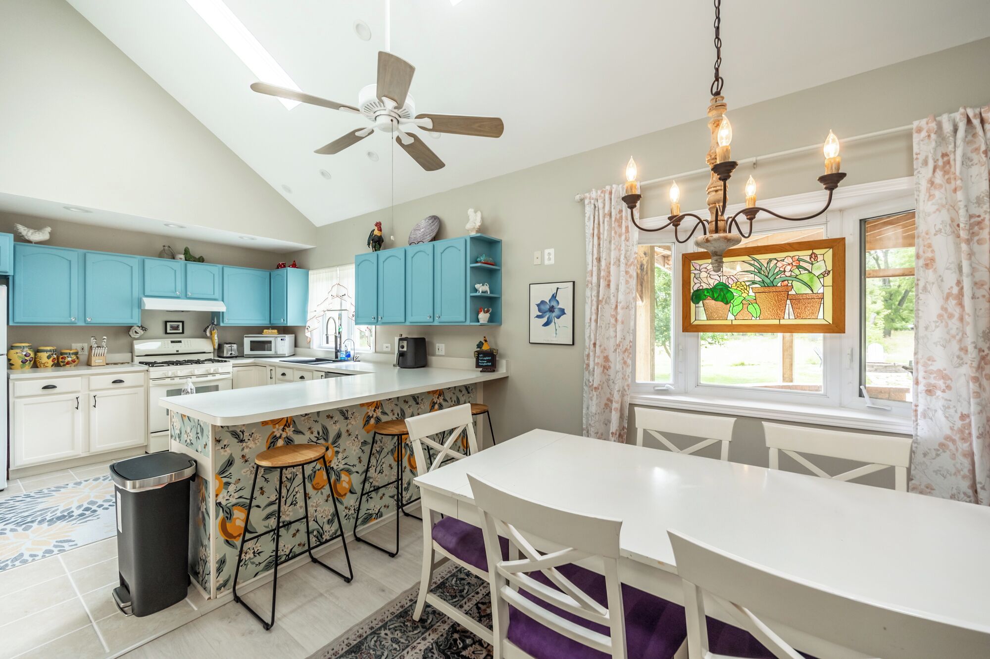 A modern kitchen with a central island, blue cabinets, and a chandelier.