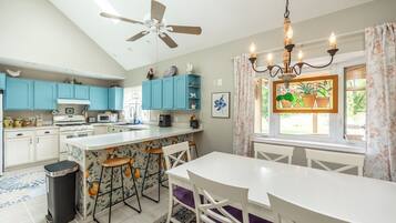 A modern kitchen with a central island, blue cabinets, and a chandelier.