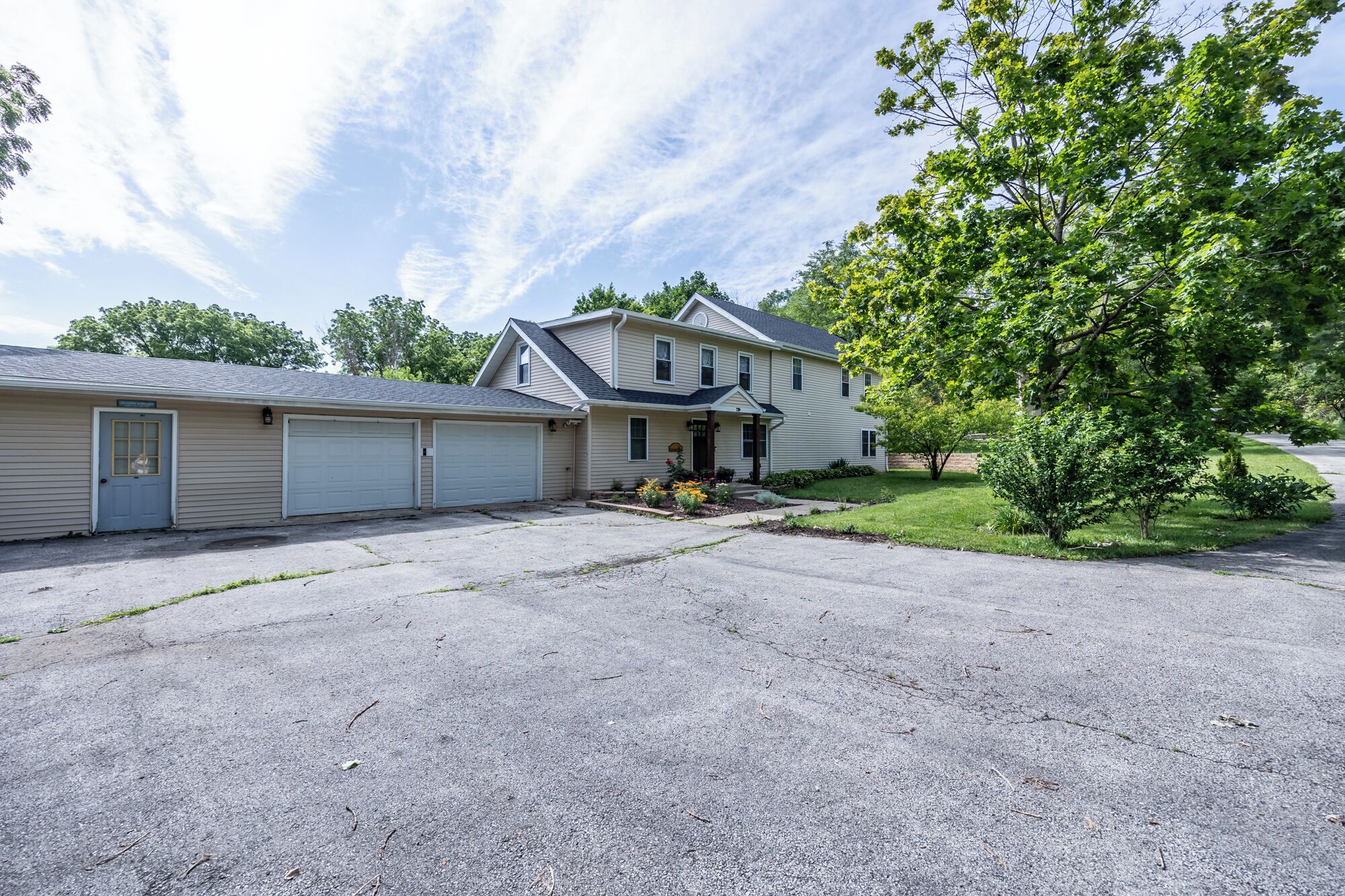 A two-story house with a garage, a front porch, and a well-maintained lawn.