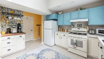 A modern kitchen with white cabinets, a blue upper cabinet, a white refrigerator, a stove, and a microwave.