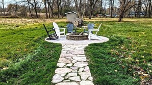 Un chemin de pierres menant à un foyer avec des fauteuils Adirondack.
