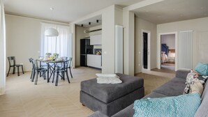 Un apartamento moderno con comedor, kitchenette y sala de estar con sofá y reposapiés.