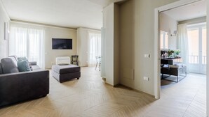 Un salón amplio con un sofá, un reposapiés y un televisor en la pared.